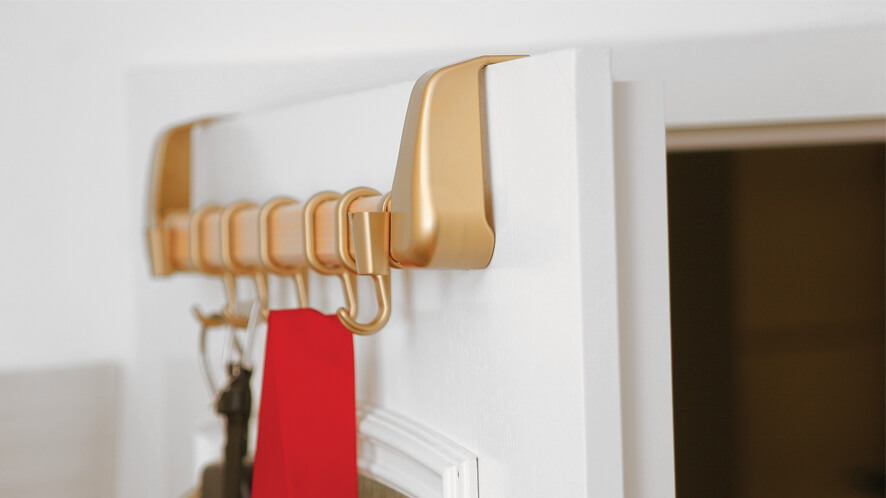 Obešalnik_nature_ZL_od blizu Prikaz zlatega obešalnika zataknjenega na vrata.