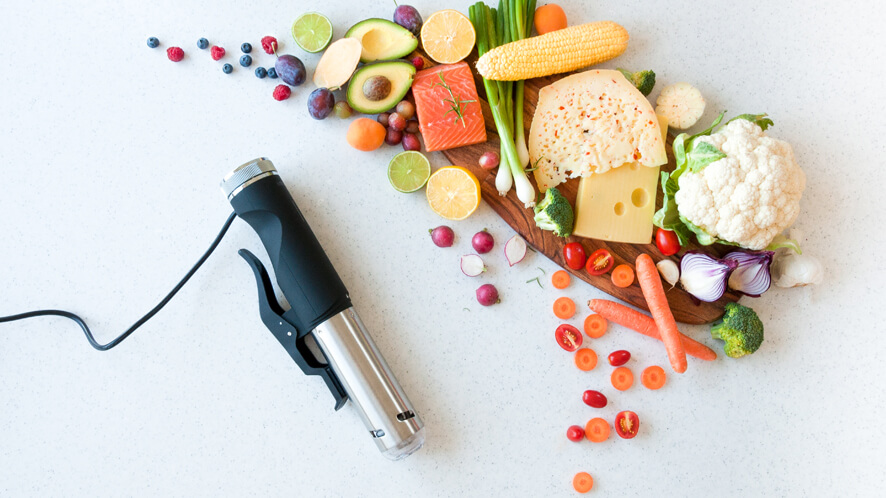 Sous Vide SVC100_zelenjava Ležeči Sous Vide kuhalnik SVC100 in različna zelenjava desno.