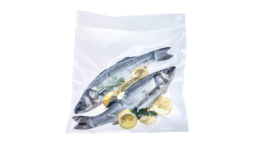 XL vrečke 100 kom_ribe Zavakuumirani ribi z limono v XL vakuumski vrečki na belem ozadju.